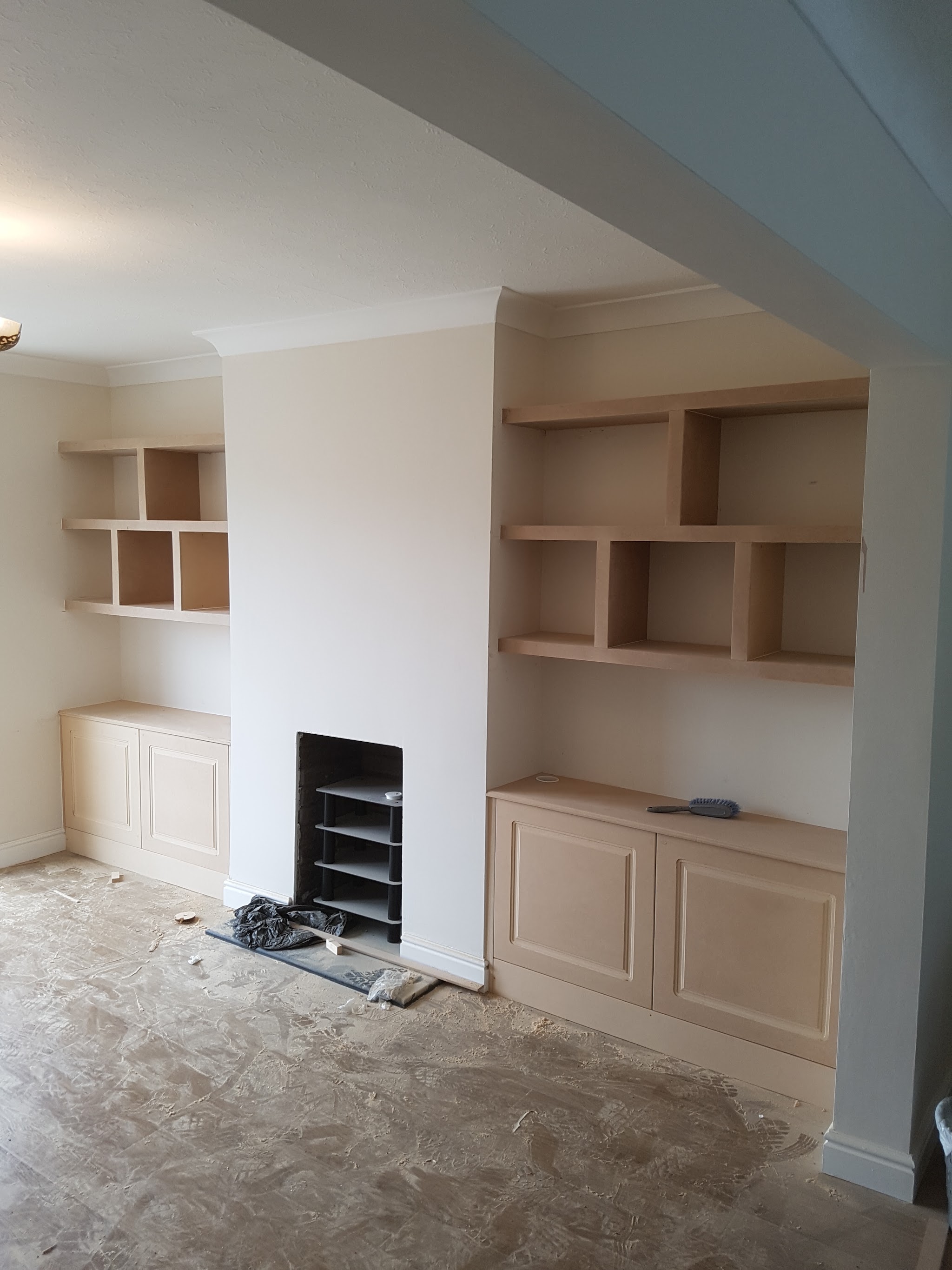Cupboards and open shelving built into both alcoves either side of a chimney breast