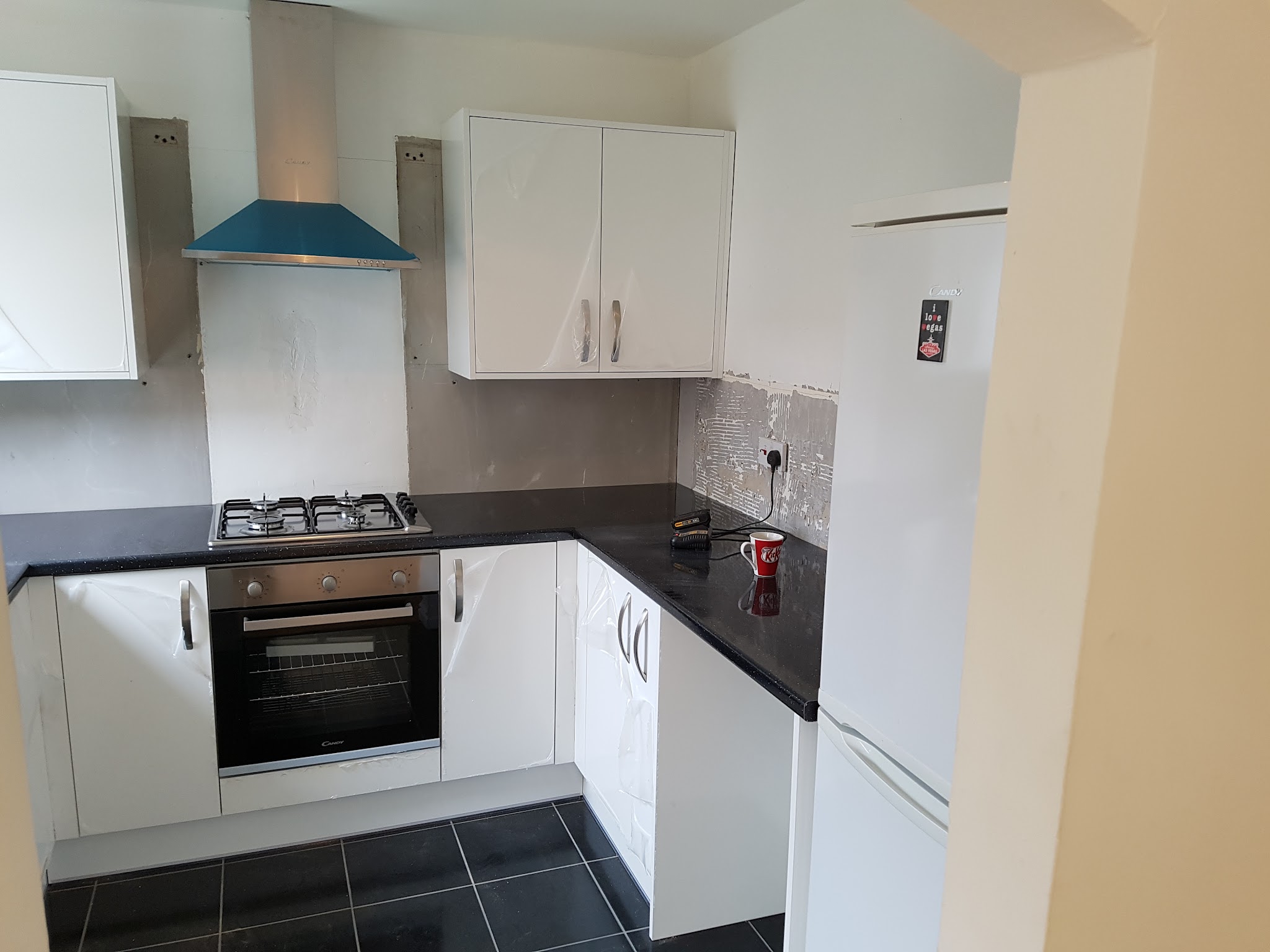 A white kitchen with black worktops, a built-in oven and a gas hob