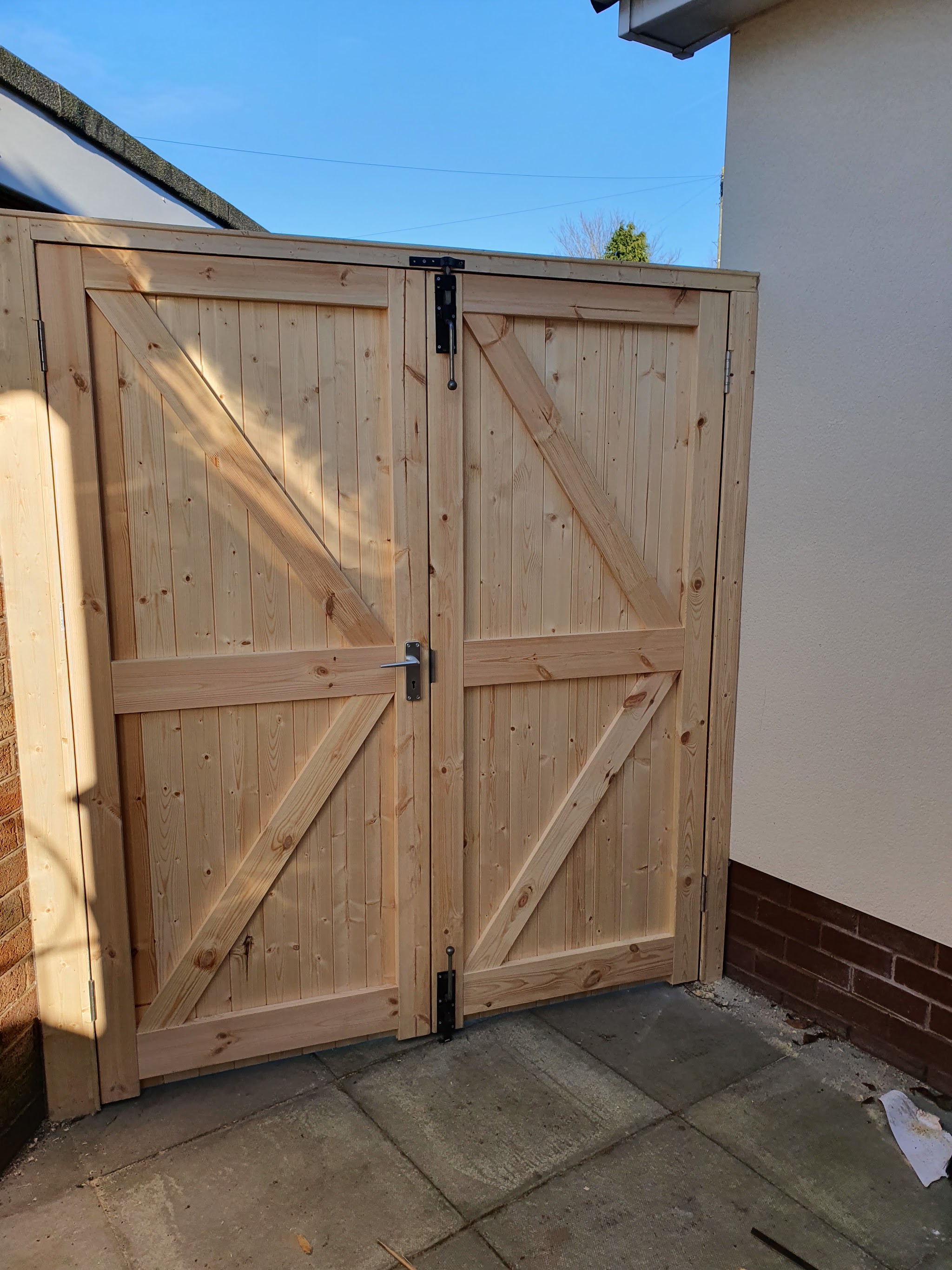 A ledged and braced timber double gate fitted at the side of a house