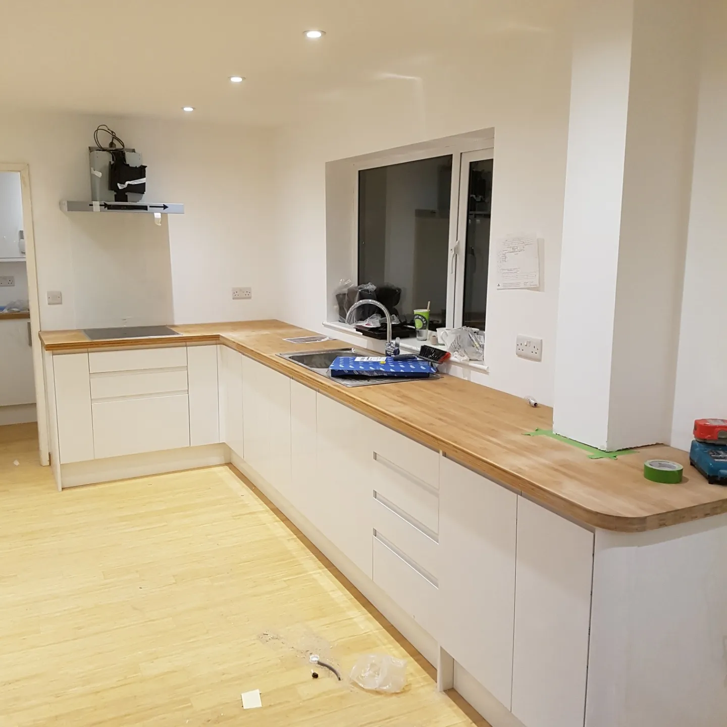 A white kitchen with a solid wood worktop running around the room